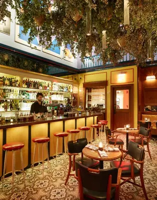 a bar in a restaurant with tables and a bartender at The Standard - East Village in New York