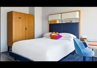 a bedroom with a white bed and a blue chair at The Standard - East Village in New York