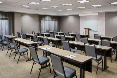 a conference room with tables and chairs and a screen at SpringHill Suites by Marriott Newark International Airport in Newark
