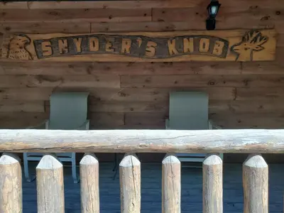 a wooden porch with chairs and a sign on a building at Snyder's Knob in Millerstown
