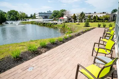a row of chairs sitting next to a pond at SpringHill Suites by Marriott Woodbridge in Woodbridge