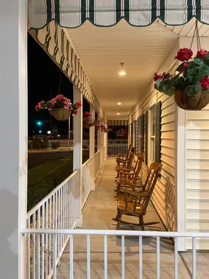 a row of rocking chairs on a porch at night at Country Inn of Hazlet in Hazlet