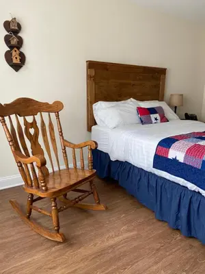 a bedroom with a wooden rocking chair next to a bed at Country Inn of Hazlet in Hazlet