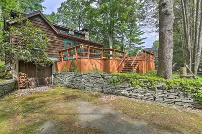 a log home with a stone retaining wall and a house at Steps to Lake Tafton Cottage with Fire Pit and Grill in Tafton