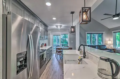 a kitchen with a stainless steel refrigerator and a living room at Unwind Fireside and Walk to Slopes! Poconos Getaway in Lake Harmony