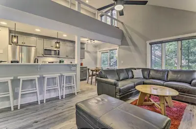 a living room with a leather couch and a kitchen at Unwind Fireside and Walk to Slopes! Poconos Getaway in Lake Harmony