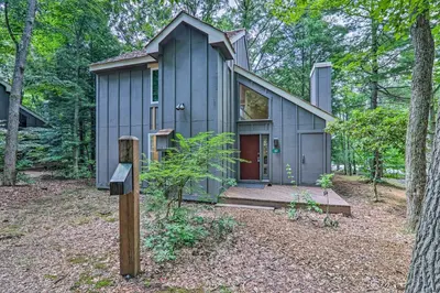 a tiny house in the woods with a sign in front at Unwind Fireside and Walk to Slopes! Poconos Getaway in Lake Harmony