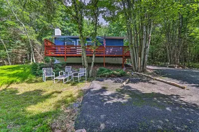 a cabin in the woods with two chairs and a house at Fire Pit and Community Perks Blakeslee Cottage! in Blakeslee