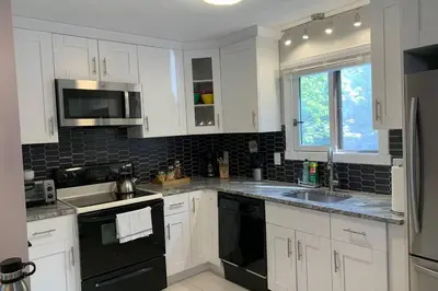 a kitchen with white cabinets and black appliances at Just renovated Camelback SKI-ON/OFF,SNOW TUBING,PAINTBALL in Tannersville