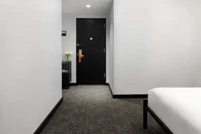 a hallway with a black door and a bed at OYO Times Square in New York