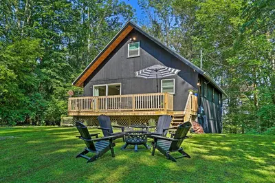 a black cabin with a table and chairs in the grass at Deck and Gas Grill Modern East Stroudsburg Home! in East Stroudsburg