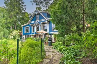 a blue house with a fence in front of it at Lakefront Poconos Retreat with Hot Tub, Near Hiking! in Bear Creek Village