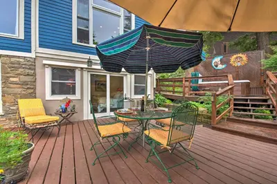 a patio with a table and chairs and an umbrella at Lakefront Poconos Retreat with Hot Tub, Near Hiking! in Bear Creek Village