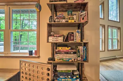 a book shelf filled with books in a room at Steps to River Big Bass Lake House with Grill! in Gouldsboro