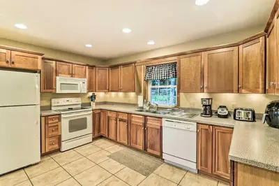 a kitchen with wooden cabinets and white appliances at Steps to River Big Bass Lake House with Grill! in Gouldsboro