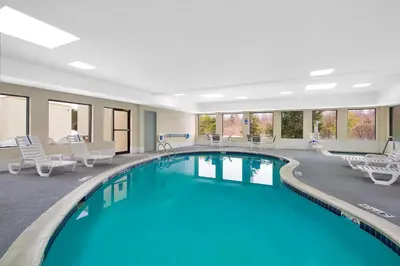 a pool in a hotel room with chairs and tables at Holiday Inn Express Harrisburg I-81 - Hershey By IHG in Manadahill