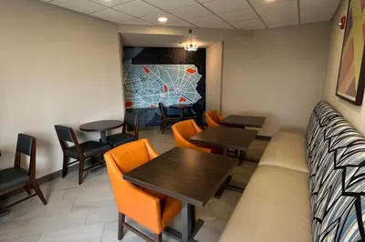 a dining room with orange chairs and tables and a bench at Holiday Inn Express Harrisburg I-81 - Hershey By IHG in Manadahill