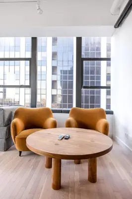 a coffee table and two chairs in a room with windows at Placemakr Wall Street in New York