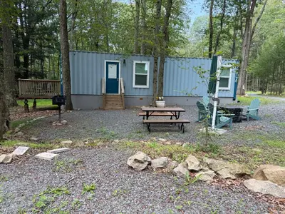 a blue cabin with a picnic table and a bench at Camptel Poconos in Albrightsville