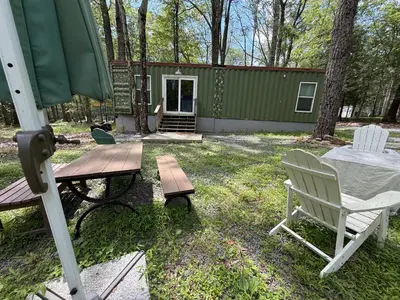 a backyard with a green cabin with a table and chairs at Camptel Poconos in Albrightsville
