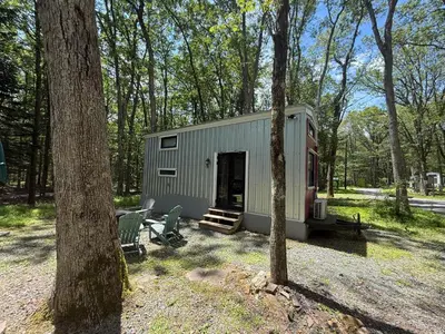 a green trailer in the middle of a forest at Camptel Poconos in Albrightsville
