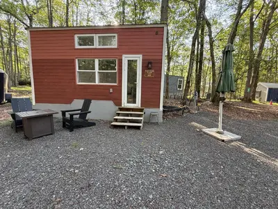 a red tiny house with a table and a patio at Camptel Poconos in Albrightsville