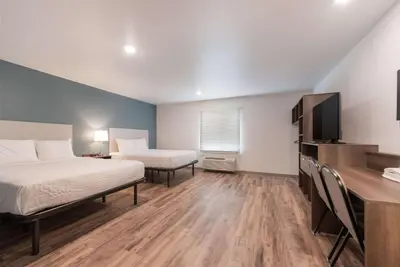 a room with two beds and a desk and a television at WoodSpring Suites Philadelphia Northeast in Philadelphia