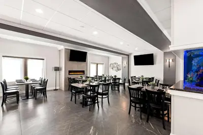 a dining room with tables and chairs and a fireplace at Best Western Plus Concordville Hotel in Concordville