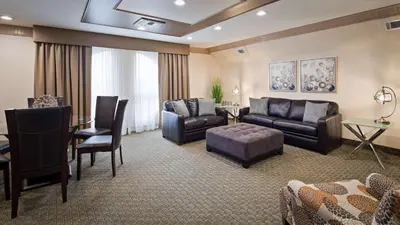 a living room with a couch and a table and chairs at Best Western Plus Concordville Hotel in Concordville