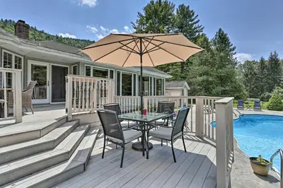 a patio with a table and chairs and an umbrella at Riverside Retreat in Catskill Mountains with Pool, Hot Tub & Game Room in Starlight
