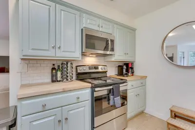 a kitchen with white cabinets and a stove top oven at Charming Swan Lake Apartment with Deck! in Swan Lake