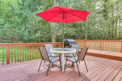 a table with chairs and a red umbrella on a deck at Charming Swan Lake Apartment with Deck! in Swan Lake