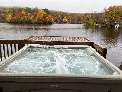 a hot tub on a deck next to a lake at Large family house on the lake in Hewitt