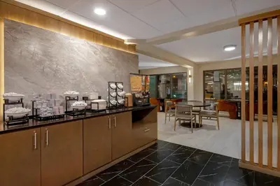 a kitchen with wooden cabinets and a dining room at Best Western Plus Meadowlands in Secaucus