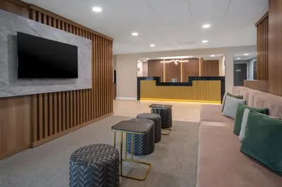 a waiting room with stools and a flat screen tv at Best Western Plus Meadowlands in Secaucus