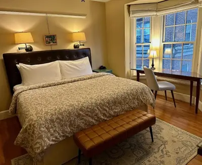 a bedroom with a bed and a desk and windows at City House Bed and Breakfast in Harrisburg