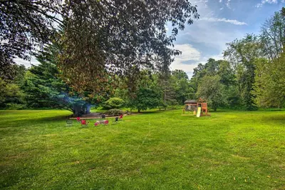 a park with red chairs in a green field at Family-Friendly Coatesville House with Fire Pit in Coatesville