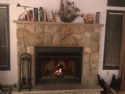 a stone fireplace with a fire in it at Cozy Pocono Cottage near Jack Frost Jim Thorpe in Albrightsville
