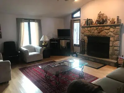 a living room with a stone fireplace and a table at Cozy Pocono Cottage near Jack Frost Jim Thorpe in Albrightsville
