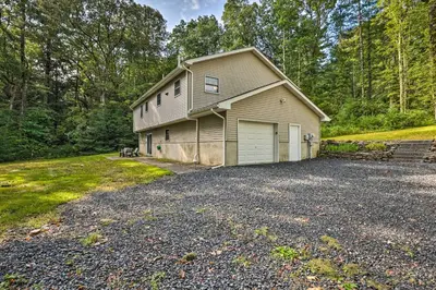 a house with a garage in the middle of a driveway at Hot Tub and Yard Stroudsburg Home in Poconos in Stroudsburg