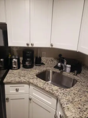 a kitchen counter with a sink and white cabinets at The Airport Lodge in Collingdale