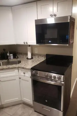 a kitchen with a stove and a microwave at The Airport Lodge in Collingdale