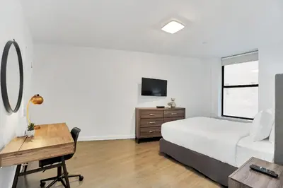 a bedroom with a bed and a desk and a television at National at 888 Sixth Avenue - Furnished Apartments in New York