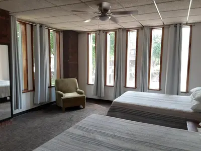 a bedroom with two beds and a chair and windows at Mountain View Lodge in Clifford