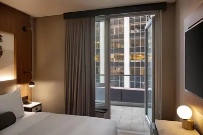 a hotel room with a bed and a balcony at Hotel Indigo NYC Downtown - Wall Street by IHG in New York