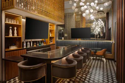 a bar with a row of bar stools and a television at Hotel Indigo NYC Downtown - Wall Street by IHG in New York
