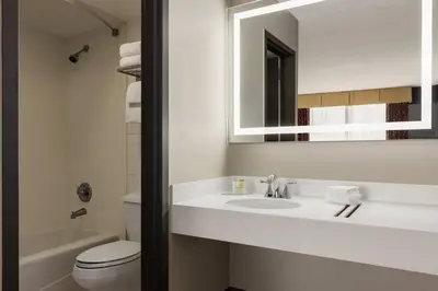 a bathroom with a sink and a toilet and a mirror at Super 8 by Wyndham Meadowlands in Carlstadt