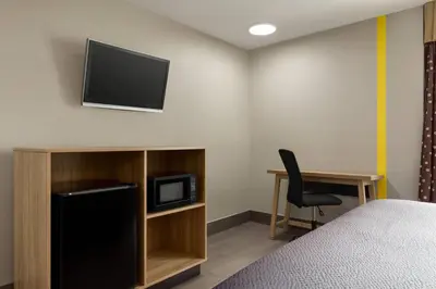a room with a bed and a desk and a television at Super 8 by Wyndham Meadowlands in Carlstadt