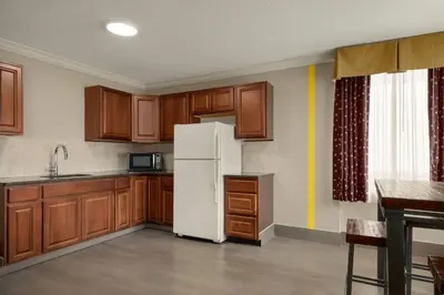 a kitchen with wooden cabinets and a white refrigerator at Super 8 by Wyndham Meadowlands in Carlstadt
