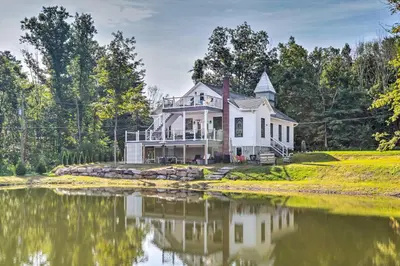 a white house with a pond in front of it at Hike and Ski! Blue Heron Brodheadsville Cottage in Brodheadsville